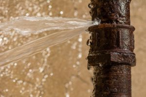 Burst Water Pipe - Water Leaking towards left of Image - Rusted damaged Pipe to the Right